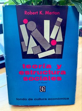 The image features a blue book titled "Teoria y estructurada sociaals" written in Spanish, which translates to "Theory of Society" in English. The book appears to be an old edition with a pink cover, placed on a wooden table or desk. The title and author's name are prominently displayed at the top of the book.