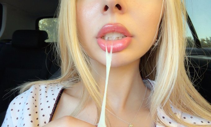 A close-up shot of a blonde woman's face showing a thick strand of stringy saliva stretching from her mouth.