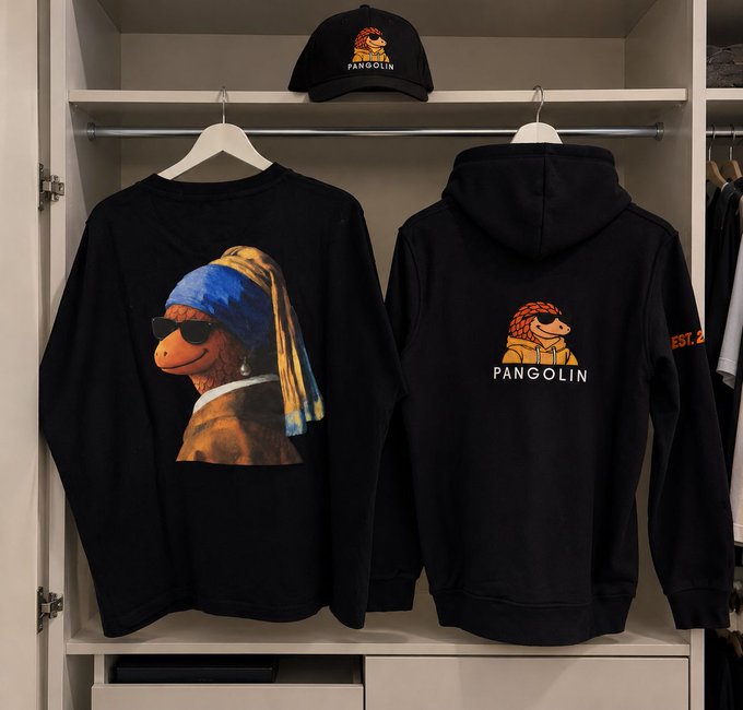 A clothing display featuring black merchandise branded 'Pangolin,' including a sweatshirt with a Vermeer 'Girl with a Pearl Earring' parody depicting a pangolin, a hoodie with the Pangolin logo, and a matching cap.
