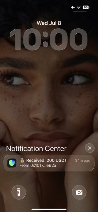 A smartphone lock screen showing 10:00 on Wed Jul 8 with a notification that reads 'Received: 200 USDT From 0x1017...eB2a 34m ago' over a portrait wallpaper.