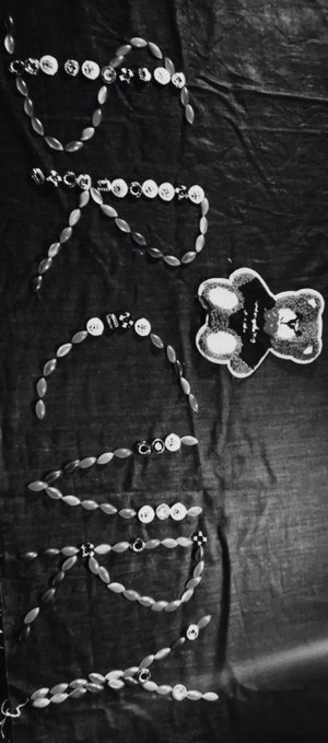 The image features a black background with white text that reads "start your day feeling safe and happy all recovered - all thanks to RCVRY, bringing mental awareness on chain". The text is arranged in a creative way using beads as letters, giving the message an artistic touch. A teddy bear can be seen sitting next to the text, adding a playful element to the scene.