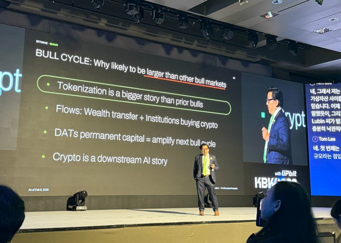 Tom Lee presents on stage at Korea Blockchain Week (KBW) 2025, standing before a slide titled "BULL CYCLE: Why likely to be larger than other bull markets" that lists key bullish catalysts including tokenization, institutional flows, DATs permanent capital, and crypto as a downstream AI story. The presentation aligns with his forecast that the current crypto bull market will be amplified by wealth transfers, institutional buying, and AI-driven digital money adoption.