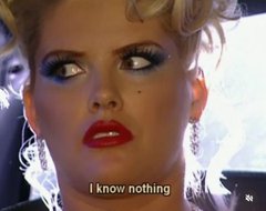 A close-up of a woman with dramatic 80s-style makeup featuring bright red lipstick and heavy blue eyeshadow, with the caption 'I know nothing' overlaid at the bottom.