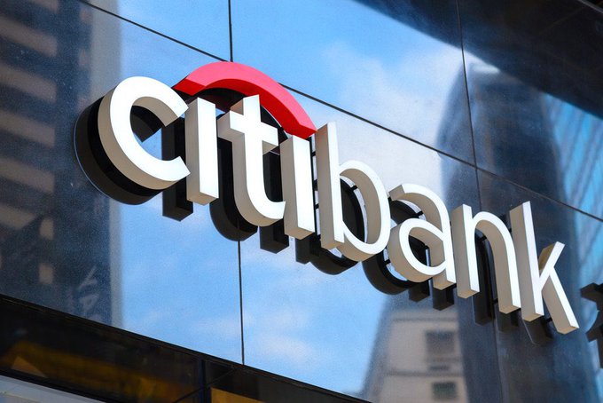 The image shows a large, white sign for the Citi Bank logo displayed prominently on a building's exterior wall. The sign features an arrow pointing upwards, which could be interpreted as a symbol of upward growth or progress. Below the logo, there is text that reads "BREAKING: CITI to launch tokenized securities of private companies $XRP". This suggests that Citi Bank might be launching a new initiative in the crypto space, possibly involving tokenized securities of private companies.