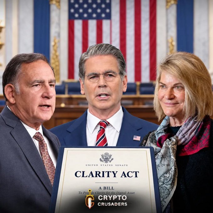 Three people stand before an American flag holding a framed copy of the Senate's 'CLARITY ACT' digital asset regulation bill, with a 'Crypto Crusaders' watermark at the bottom.