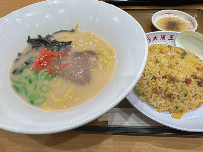 A meal consisting of a large bowl of ramen with beef and vegetables, served alongside a plate of fried rice and a small cup of coffee.