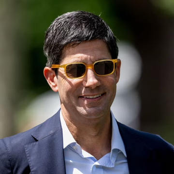 A middle-aged man with dark hair, wearing yellow-framed sunglasses, a navy blazer, and a light blue shirt, smiles outdoors. While no text is visible on the image, the accompanying post about Federal Reserve liquidity and Bitcoin suggests this may be a financial analyst or commentator discussing monetary policy's impact on cryptocurrency markets.