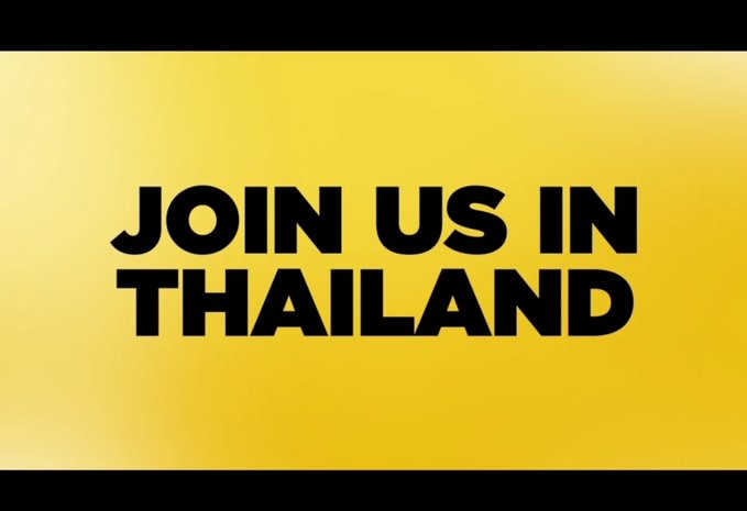 A bright yellow screen with bold black text reading 'JOIN US IN THAILAND'.