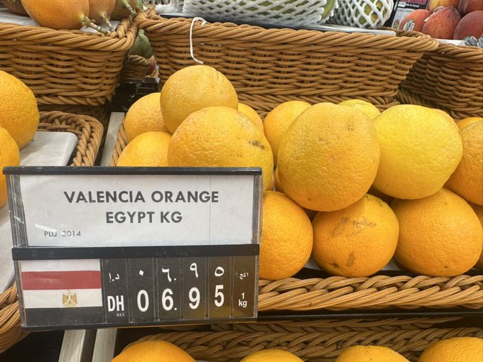 A display of Valencia oranges from Egypt (PLU 3014) priced at 6.95 DH/kg at what appears to be a Dubai supermarket, illustrating the post's theme of seemingly identical products carrying unexpectedly varied price tags.

The sign reads "VALENCIA ORANGE EGYPT KG" with "PLU 3014" and the price "06.95 DH" for 1 kg.