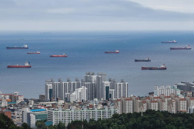 An aerial view of a coastal city with numerous cargo ships and tankers anchored offshore, juxtaposing urban development against busy maritime activity. The image visually mirrors the post's theme of market uncertainty, suggesting that what appears as a downturn may actually represent a gathering of opportunities waiting to be seized.