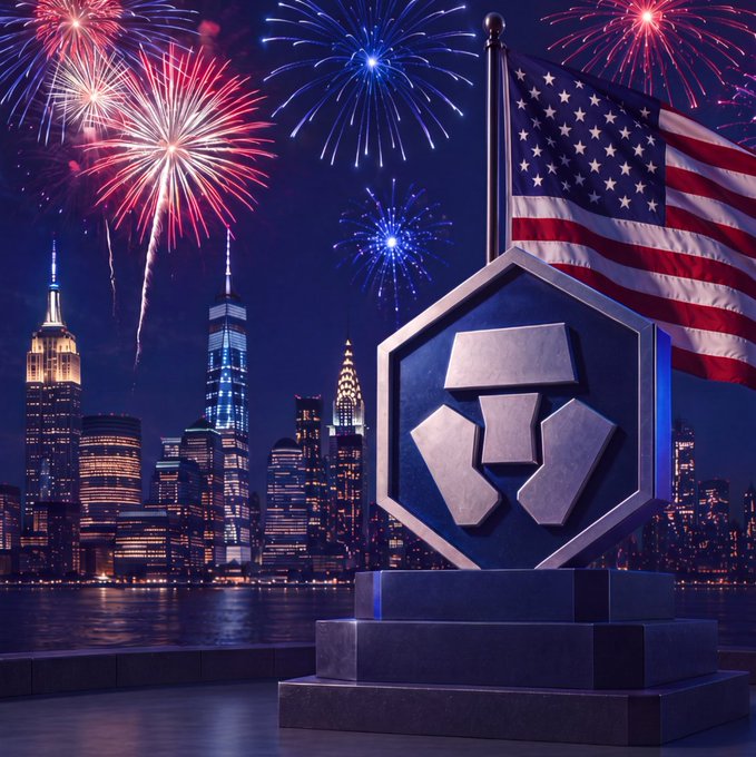 A patriotic scene featuring a metallic shield/trophy emblem with an American flag against a backdrop of the New York City skyline at night with colorful fireworks exploding in the sky.