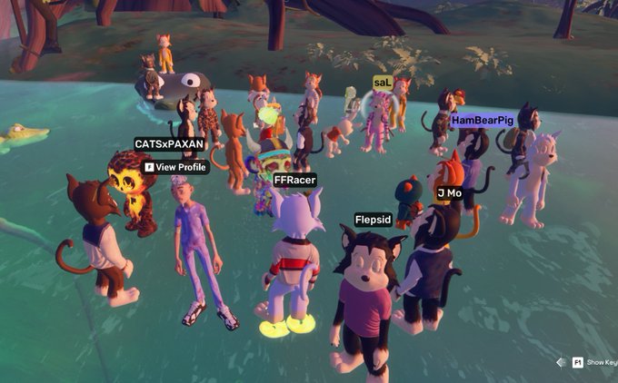 A screenshot from a 3D animated online game showing numerous anthropomorphic cat avatars gathered in a circle near water, with player names visible above their heads including "CATSxPAXAN", "FFRacer", "saL", "HamBearPig", "J Mo", and "Flepsid".