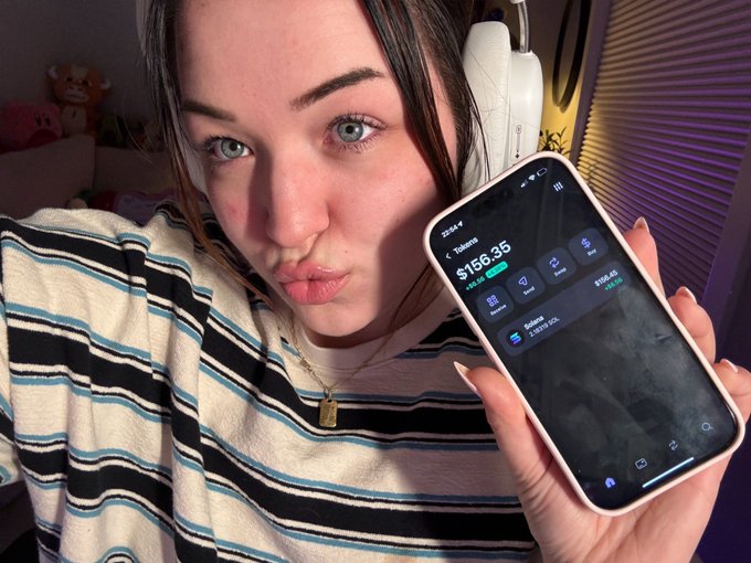 A young woman wearing a striped shirt holds a smartphone that has a screen displaying the word "sol", and she appears to be posing with her phone. The post suggests that someone is tracking their buying progress, as indicated by the number 212 on the phone screen. The context seems to be related to Bitcoin trading or cryptocurrency-related matters.