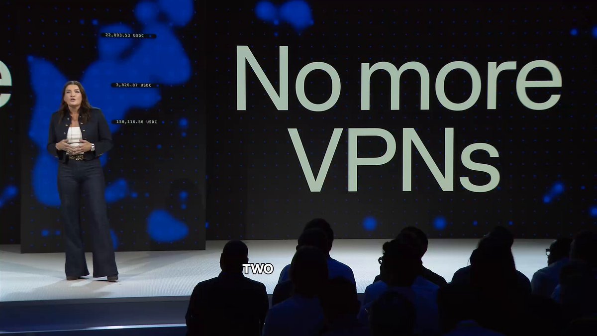 The image shows a woman standing on stage at an event, giving a speech about cryptocurrency options available through Coinbase. The audience appears engaged as they listen to her presentation. The text displayed on the screen behind her reads "No more VNP" which is related to the topic of the presentation.