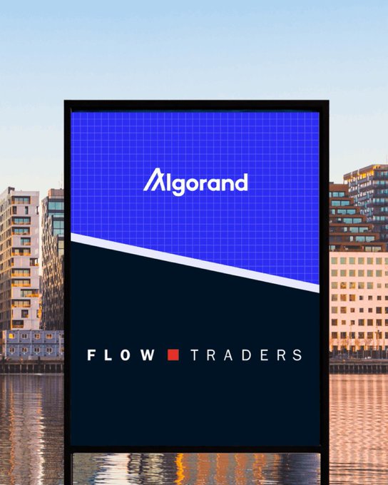 A vertical banner displayed along a waterfront showcases the "Algorand" logo on a blue grid background and "FLOW TRADERS" in white text on a dark navy section, visually representing the partnership between the two companies highlighted in the post about institutional liquidity in blockchain finance.