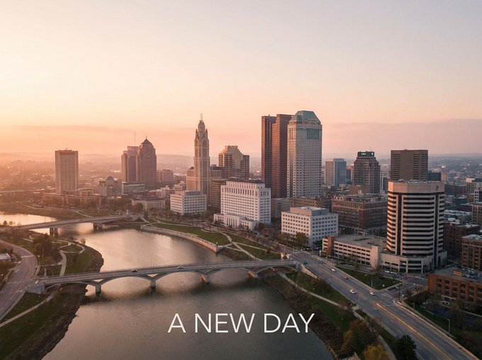 A sunrise over the Columbus, Ohio skyline with the Scioto River bridges bathed in golden light, overlaid with the text "A NEW DAY."

The caption's "A NEW DAY" text pairs with the dawn imagery to symbolize the financial reset described in the post—suggesting a new economic chapter as Buffett's $397B cash position and Dalio's warnings about the breakdown of the petrodollar-based monetary order signal a turning point.
