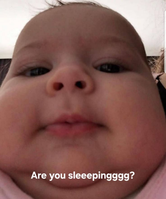 A close-up selfie of a baby with chubby cheeks, accompanied by the overlaid text 'Are you sleeepingggg?'.
