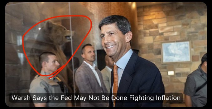 A news image of Fed official Warsh smiling, with a circled area highlighting a reflection of a bear in the glass behind him, captioned "Warsh Says the Fed May Not Be Done Fighting Inflation".