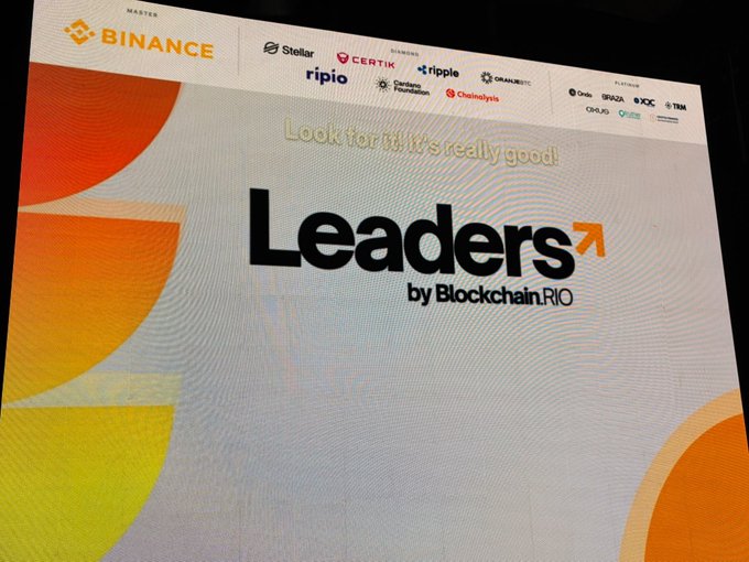 A signage display for "Leaders by Blockchain RIO," sponsored by Binance and featuring logos of notable partners including Stellar, Certik, Ripple, OVB, Chainalysis, and others. The event branding aligns with the post's sentiments about witnessing the crypto industry's evolution and the development of foundational onchain use cases.
