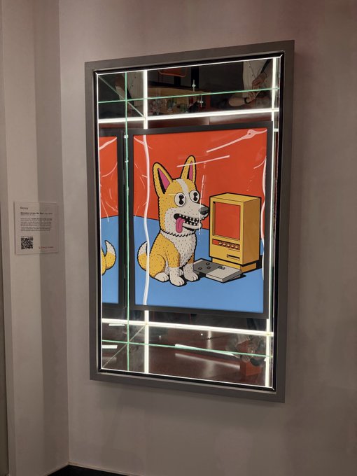 An illuminated LED-framed mirror displays a colorful cartoon artwork featuring a happy dog sitting next to a retro computer and joystick against an orange background.