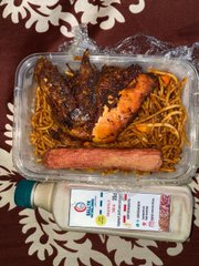 A takeout container with grilled chicken and noodles, a sausage, and a wrapped package of cheese labeled 'President', sitting on a surface with snowflake decorations.