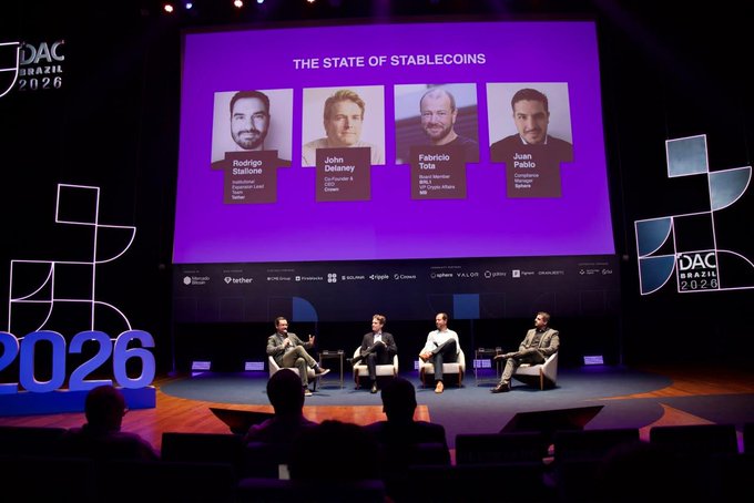 A panel discussion titled 'THE STATE OF STABLECOINS' takes place on stage at the 'JDAC Brazil 2026' conference, featuring speakers Rodrigo Dabus, John Delaney, Fabricio Tota, and Juan Pablo on a large screen.