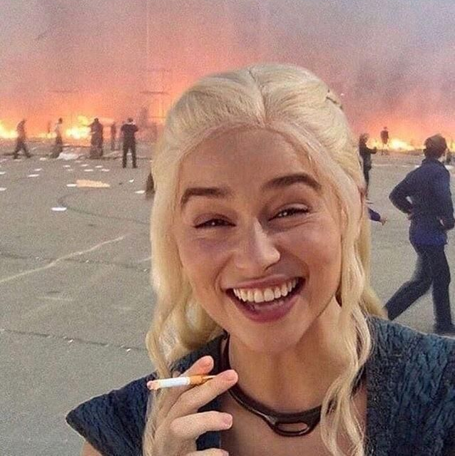 The image features a blonde woman with blue eyes who appears to be smiling while holding a cigarette. She has blonde hair styled in loose waves that fall over her shoulders. The background of the photo shows a crowd of people standing around, possibly at an event or gathering. There is also a fire burning behind them, adding to the atmosphere of the scene. The caption on the image reads "Just bought !" and "50,000 $CHZ for 1,240 USD!".