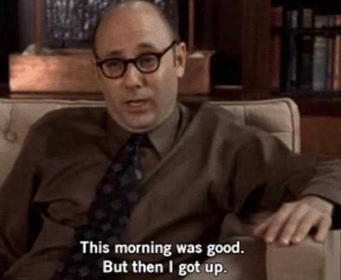 A bald man with glasses sits on a couch saying, 'This morning was good. But then I got up.'