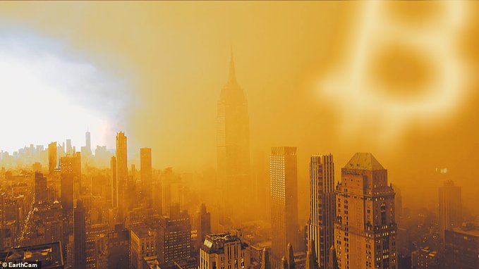 A hazy, orange-tinted photograph of the New York City skyline features a giant Bitcoin 'B' logo glowing in the smog-filled sky above the Empire State Building.