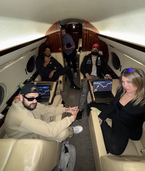 A group of people sits inside a private jet, each working on laptops displaying stock/crypto charts, symbolizing a strategic trade or portfolio swap. The image visually reinforces the post's theme of "Swapping my $PUMP for $ANSEM," as the casual yet focused trading setup mid-flight suggests actively reallocating between trending crypto tokens.