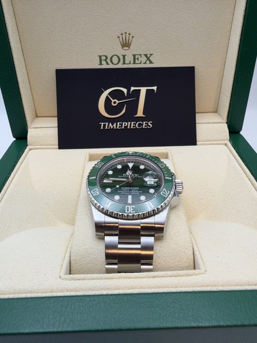 A silver Rolex Submariner watch with a distinctive green dial and bezel, presented in its green Rolex presentation box alongside a 'CT Timepieces' card.
