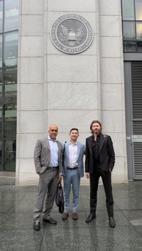 Three men posing for a photo in front of a building displaying the U.S. Securities and Exchange Commission seal.