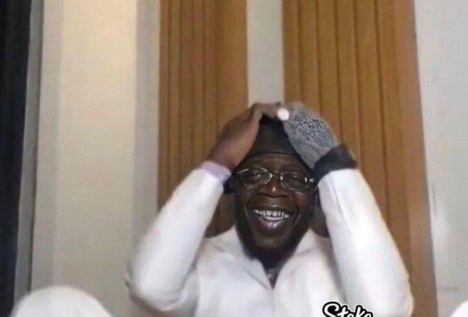 A man wearing glasses and a white shirt smiles widely while holding both hands on his head, appearing joyful or exasperated, with a wooden panel background and a "Sicks" watermark in the corner. The caption's playful phrase about not wanting "Kaito" back is paired with the meme, using the man's reaction image as a humorous response to online commenters.