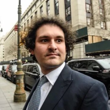 A man in a navy suit and patterned tie stands on a city sidewalk lined with parked cars and tall buildings, likely outside a courthouse or office. The image appears to depict Sam Bankman-Fried, the former FTX CEO, connecting to the post about the upcoming Netflix series chronicling FTX's rise and fall.