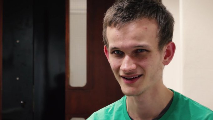 A young man with short brown hair wearing a green shirt smiles at the camera.
