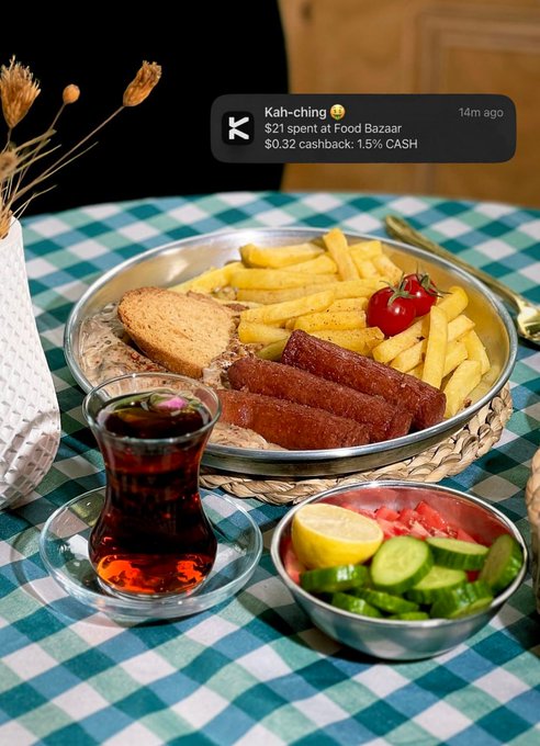 A Turkish breakfast spread of fries, sausages, bread, tea, and vegetables is shown with a notification: "Kah-ching 😋 $21 spent at Food Bazaar $0.32 cashback: 1.5% CASH 14m ago".