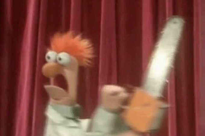 A frantic-looking red-haired Muppet from The Muppets brandishes a chainsaw wildly in front of a red curtain. The image humorously illustrates the caption's joke about overeager commenters offering unsolicited "help" to boost a project's visibility, with the chaotic chainsaw-wielding Muppet representing the destructive, misguided nature of such interference.