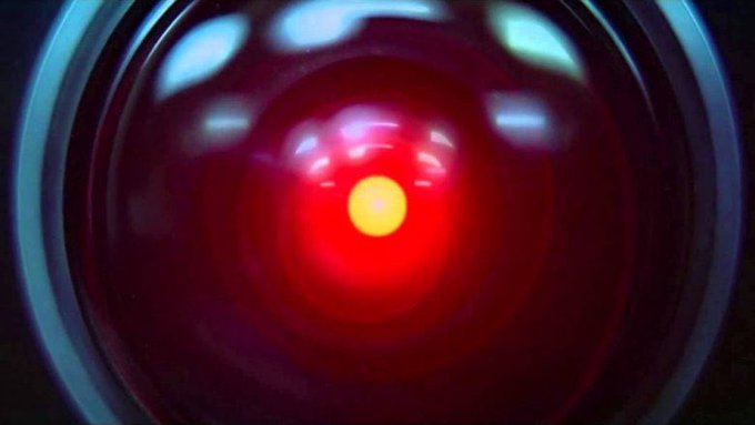 A close-up of a glowing red circular object with a bright yellow center, resembling HAL 9000's eye from 2001: A Space Odyssey.