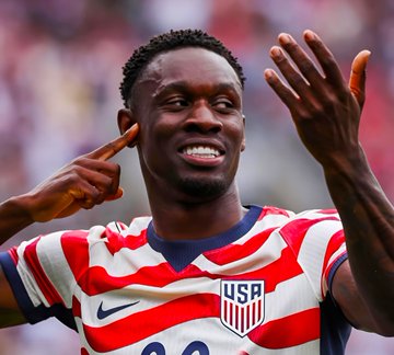 Folarin Balogun, wearing the USMNT #20 jersey, celebrates on the field, in reference to a $9,500 bet placed against him scoring against Belgium on Polymarket that would pay out $15,430.65.