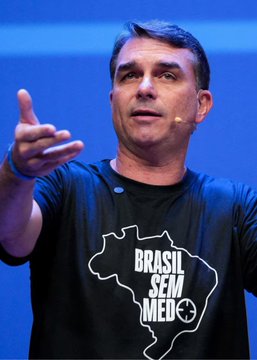 A man wearing a headset microphone and a black t-shirt featuring the outline of Brazil with the text 'BRASIL SEM MEDO' speaks on a stage with a blue background.