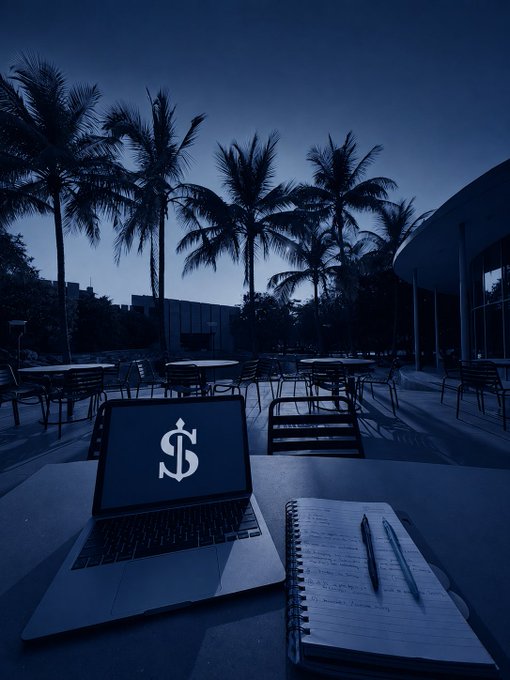 A moody blue-tinted outdoor scene showing an open laptop with a dollar sign on the screen next to a handwritten notebook, with palm trees in the background.