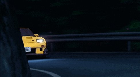 llor of a yellow car with license plate "8857" drives on the right side of a dark road, illuminated by headlights and surrounded by trees.
