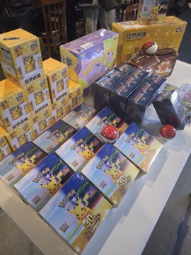 A display of Pokémon trading card game merchandise on a white surface, featuring multiple boxes of what appears to be Detective Pikachu-themed TCG products.
