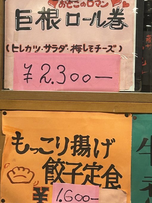 A Japanese restaurant menu displaying '巨根ロール巻' (Giant Roll) for ¥2,300 and 'もっちり揚げ餃子定食' (Crispy Fried Gyoza Set) for ¥1,600, with handwritten ingredients like ヒレカツ, サラダ, 梅しそチーズ.