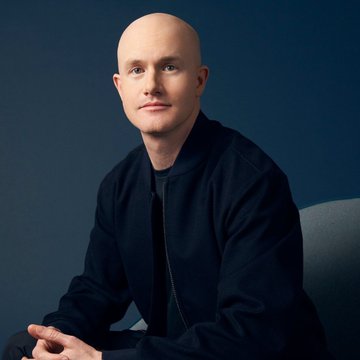 A bald man wearing a black bomber jacket sits against a dark blue background in this professional portrait-style photograph. The image appears to accompany an article about Coinbase CEO Brian Armstrong's bullish outlook on Bitcoin, specifically his prediction that the cryptocurrency could reach $400,000 by 2030 due to institutional adoption, with the subject likely being Armstrong himself.