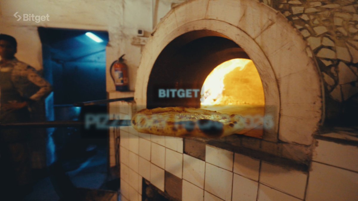 The image features a pizza oven with a pizza inside, ready for baking. The oven has a white exterior and a black interior, creating an interesting contrast. A person can be seen standing next to the oven, likely preparing or checking on the pizza. The photo also includes text that reads "proof that pizza and crypto are the perfect combo Still not over the #BitgetSlice vibes #PizzaWithBitget". This message seems to be a playful commentary about combining the enjoyment of pizza with the excitement of cryptocurrency.