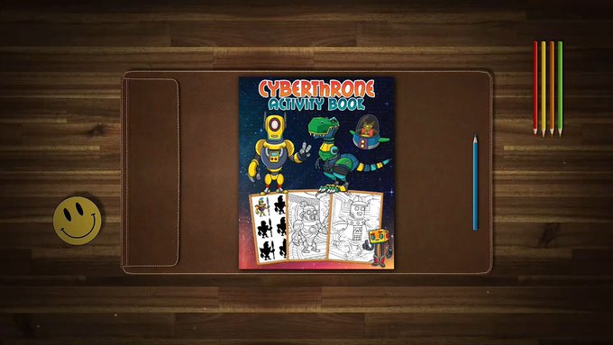 A 'CYBERTHRONS Activity Book' for ages 2 and up lies on a brown desk pad, featuring robot and astronaut illustrations, accompanied by colored pencils, a blue pencil, and a smiley face emoji on a wooden surface.
