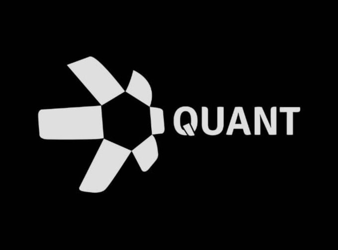 The image displays the white Quant (QNT) logo, featuring a stylized pinwheel or star-like emblem next to the bold "QUANT" text on a black background. This visual ties directly to the post's discussion of QNT's involvement in the U.S. On-Chain Money Initiative, while also being contrasted with Stellar (XLM) and DTCC's partnership announcement.