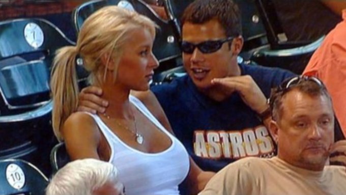 A couple of people are sitting down together, possibly watching a baseball game or enjoying each other's company. The woman has blonde hair and is wearing sunglasses while the man next to her is also wearing sunglasses and a blue shirt with the word "astros" on it. There are some chairs around them, suggesting that they might be at an indoor event like a stadium where people gather to watch sports or events together. The image caption reads: "You know I bought Solana at $40 years back and it went to $290 but I didn't sell and now it'S back at my entry".
