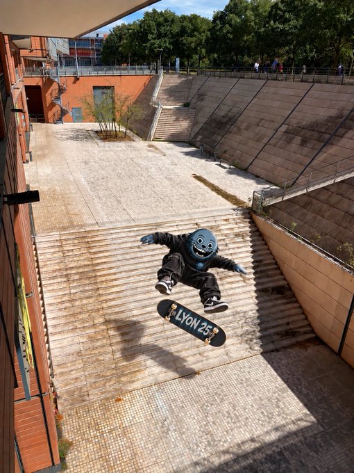 A skateboarder in a black mask and dark clothing performing a trick down a long set of stone steps, with their skateboard labeled 'LYON 25'.